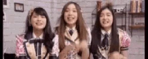 three girls in uniforms are standing next to each other and smiling .