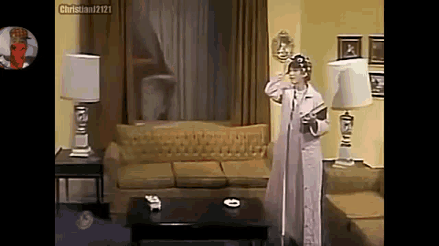a woman is standing in a living room next to a couch and a table holding a microphone .