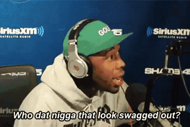 a man wearing headphones and a green hat is talking into a microphone and says who dat nigga that look swagged out