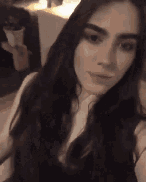 a woman with long dark hair is taking a selfie with her phone .