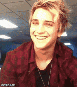 a young man wearing a red plaid shirt is smiling
