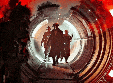 a group of people are walking through a tunnel with red lights