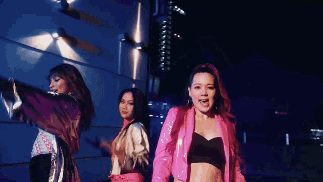 a group of women are dancing in front of a building at night