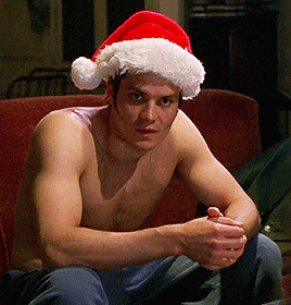 a shirtless man wearing a santa hat sitting on a couch