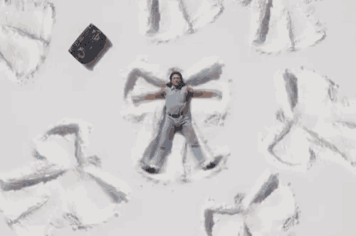 a man is laying in the snow and making a snow angel .