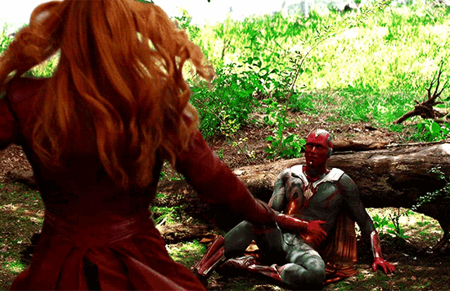 a woman in a red dress is standing next to a man in a superhero outfit