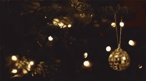 a gold disco ball ornament hangs from a christmas tree