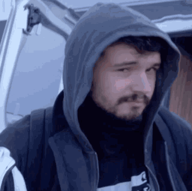 a man with a beard wearing a hooded jacket and a backpack .