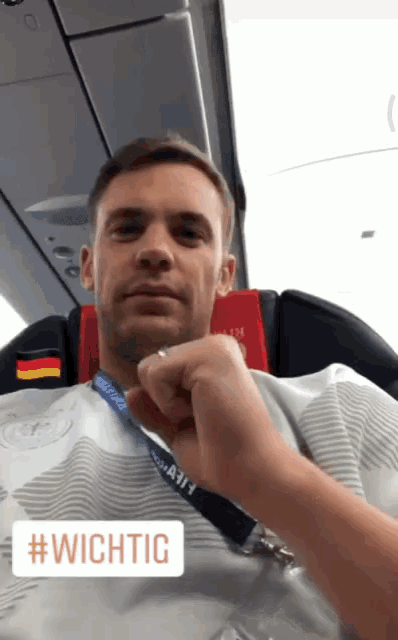 a man sitting on a plane with a #wichtig sticker