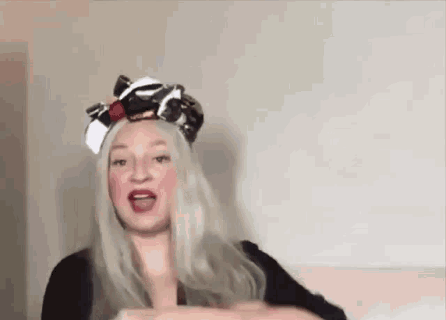 a woman wearing a wig and a scarf on her head is sitting on a couch .