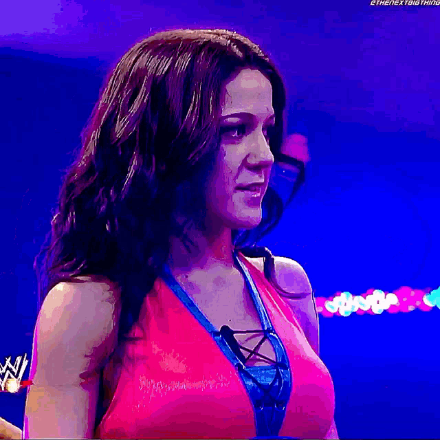 a woman in a pink top is standing in front of a purple background ..
