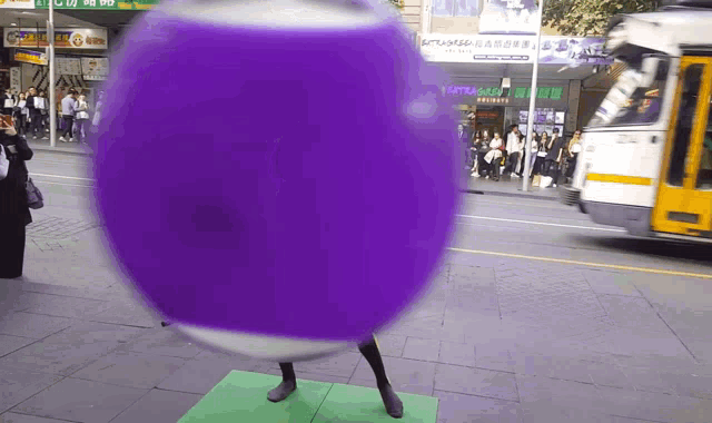 a purple ball is on the sidewalk in front of a store that says ' a' on it