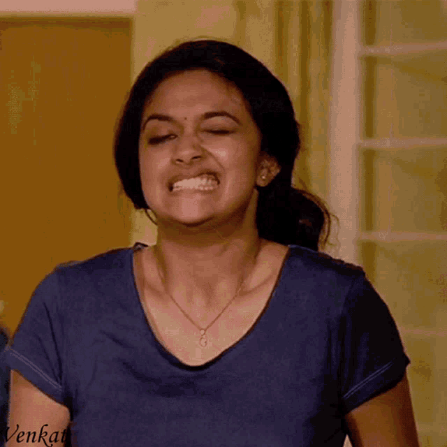 a woman wearing a blue shirt and a necklace with the name venkat on the bottom
