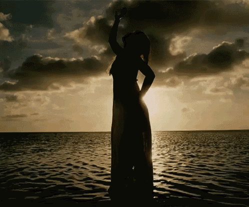 a silhouette of a woman standing in the water