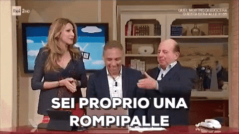 a woman and two men are sitting at a desk with the words sei proprio una rompipalle written on the screen