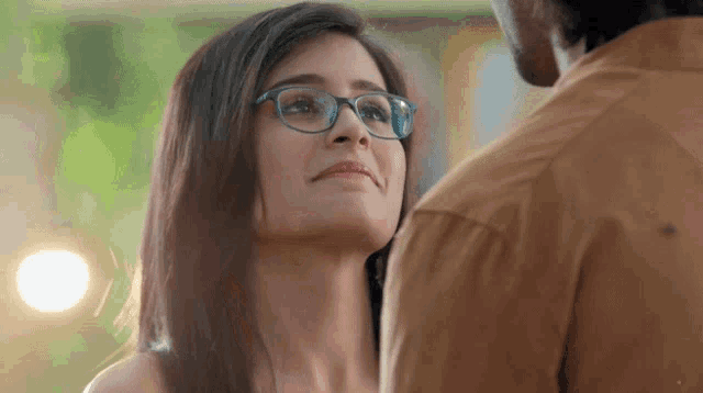 a woman wearing glasses is looking up at a man