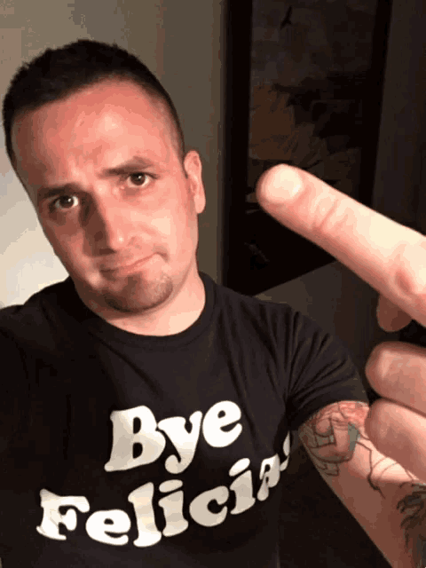 a man wearing a shirt that says bye felicia is giving the middle finger