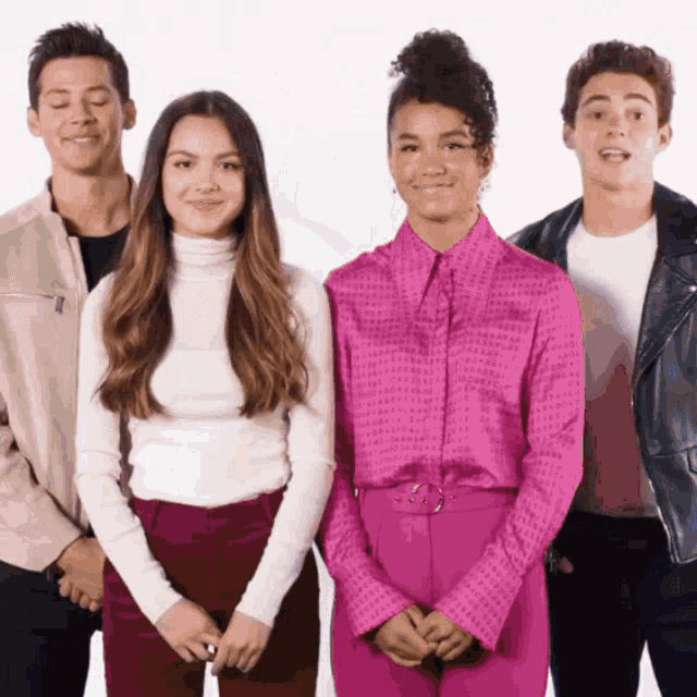 a group of young people standing next to each other with one wearing a pink shirt