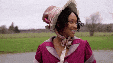 a woman wearing a pink hat and a purple dress smiles