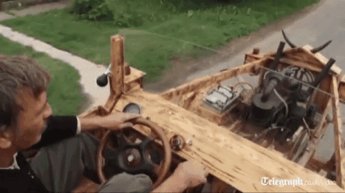 a man is driving a wooden boat with a telegraph.co.uk logo behind him