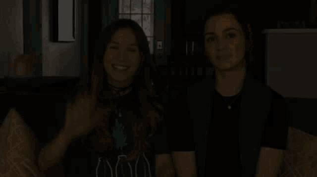 two women are sitting on a couch and one is wearing a t-shirt that says ' 000 ' on it