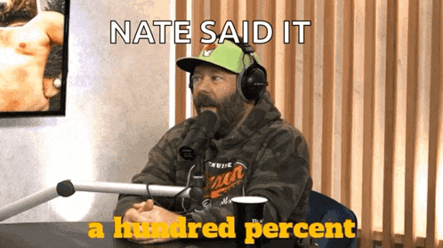a man wearing headphones is sitting at a table with the words nate said it a hundred percent