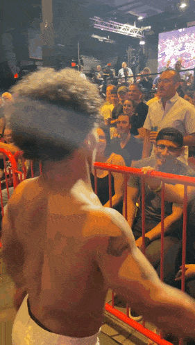 a man with a tattoo on his arm stands in front of a crowd of people