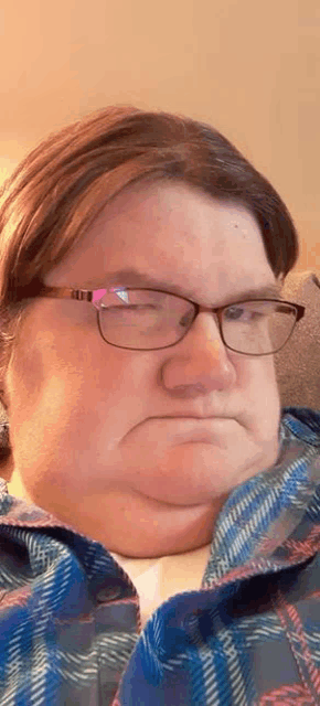 a close up of a woman wearing glasses and a plaid shirt .