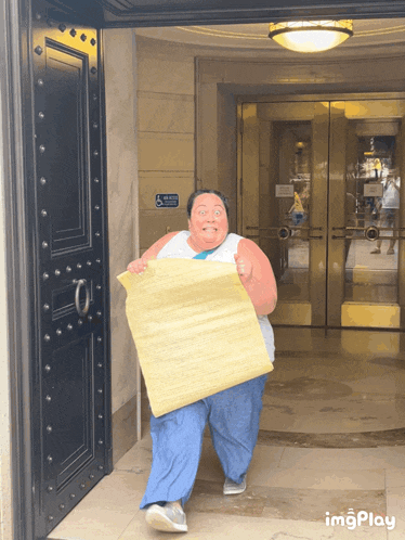 a man is carrying a large piece of paper in front of a door that has a handicap accessible sign on it