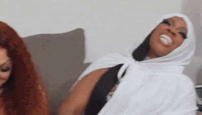 two women are sitting on a couch and one of them is wearing a white veil .