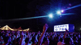 a crowd at a concert with a sign that says happy 0.796