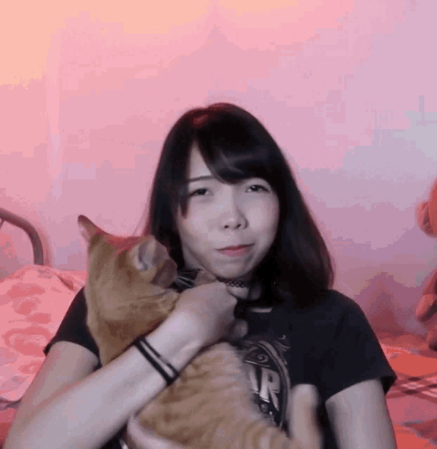 a woman is holding an orange cat in her arms