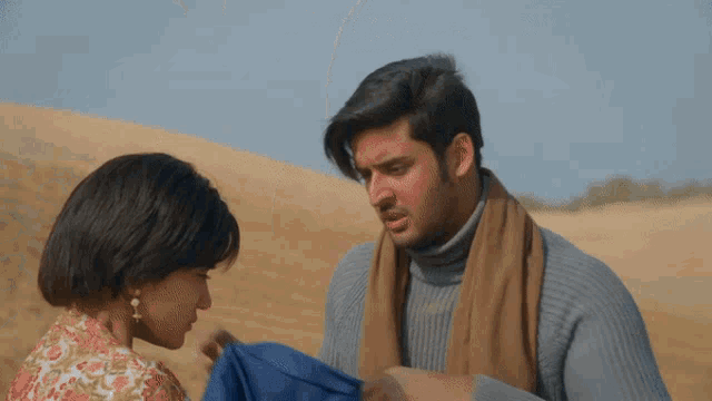a man and a woman are standing in the desert and the man is covering his face