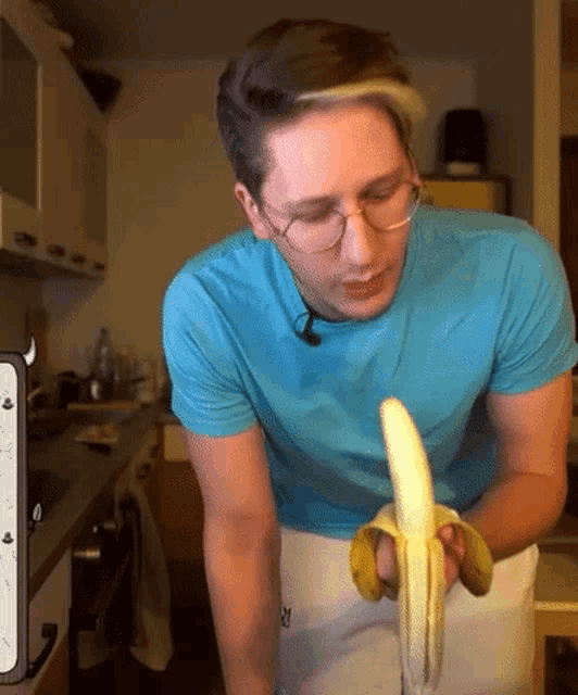 a man in a blue shirt is holding an opened banana