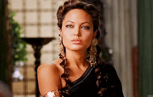 a close up of a woman wearing earrings and a braided hairdo .