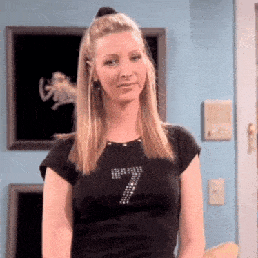 a woman wearing a black t-shirt with the number seven on it is standing in a room .