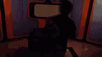 a silhouette of a man sitting in front of a television