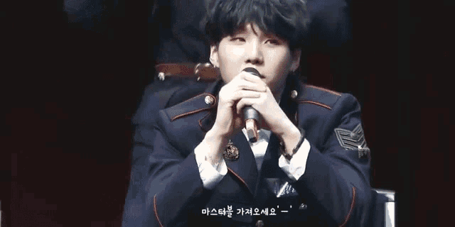 a man in a suit is singing into a microphone while sitting on a stage .