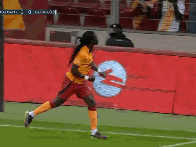 a soccer player celebrates a goal in front of a scoreboard that says galatasaray 1-0