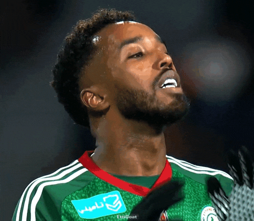 a soccer player wearing a green jersey with a blue sticker that says eti goat on it