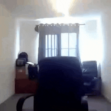 there is a chair in the middle of a room with a window in the background .