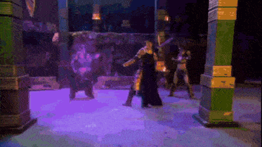 a group of people are standing on a stage with purple lights behind them