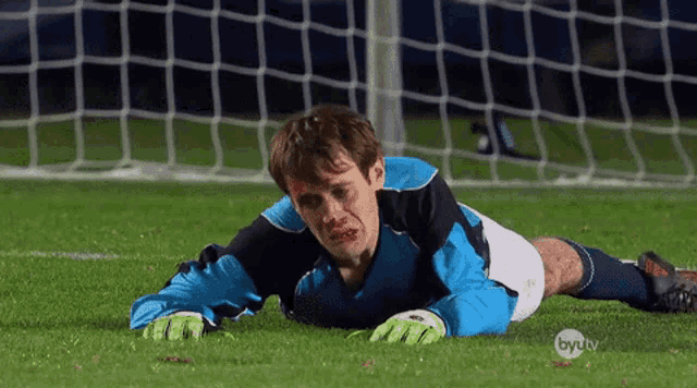 a soccer player is laying on the field with a byu tv logo in the corner