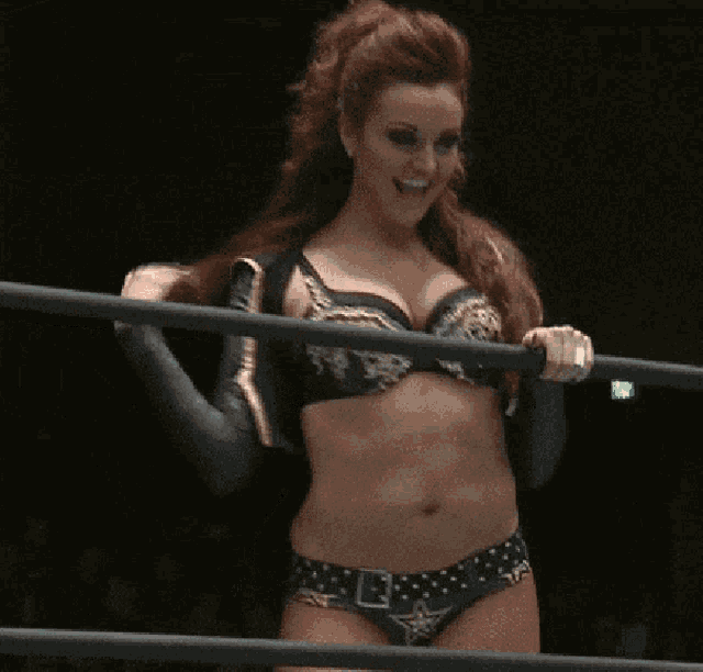 a woman in a wrestling ring is smiling and holding a rope