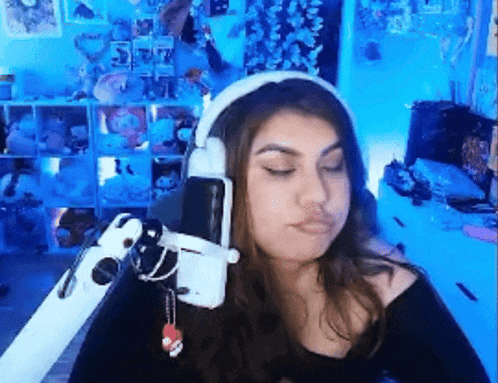 a woman wearing headphones is sitting in front of a microphone and making a funny face .