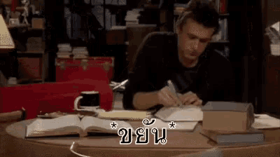 a man is sitting at a desk with a book and a pen .