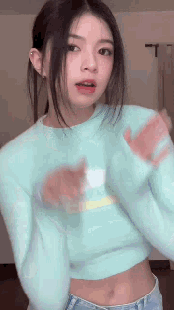 the girl is wearing a blue sweater and jeans and is dancing .