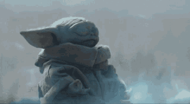 a baby yoda from star wars is sleeping in a blanket .