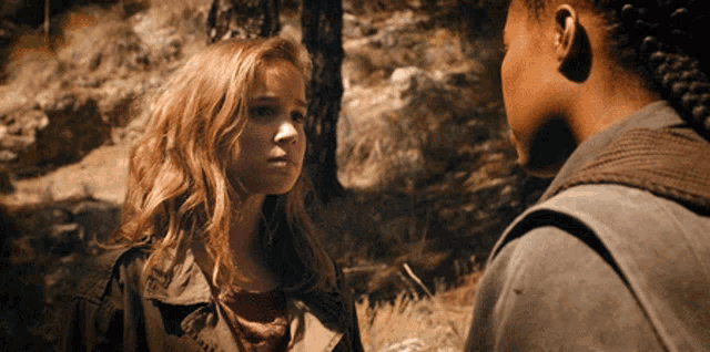 two girls are standing next to each other in a forest