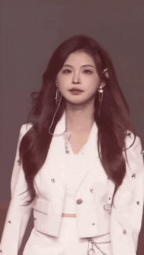 a woman with long red hair is wearing a white suit